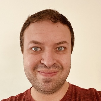 Photo of Caleb Lamont, red-orange shirt, short brown hair, with a subtle smile.