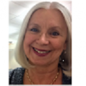 Photo of Cathy Matresse, dark shirt, necklace and earrings, gray hair in shoulder-length bob, smiling.